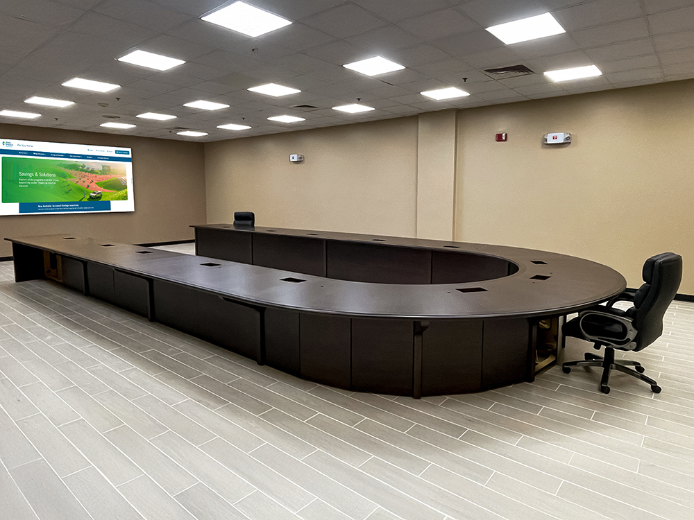 Large custom U-shaped conference room table with deep, dark wood veneer for videoconferencing including AV integration