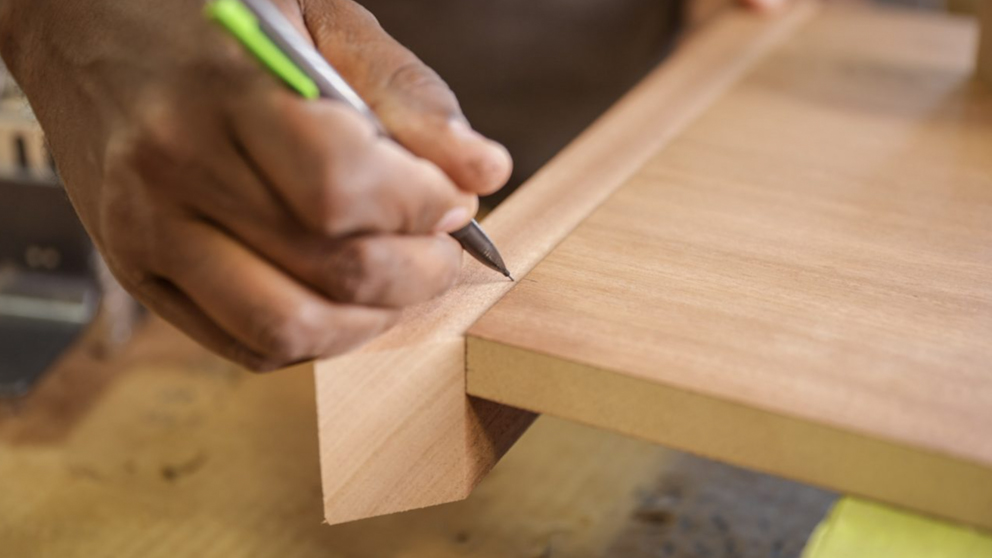 Craftsperson hand-marking a custom conference table component during fabrication at Paul Downs Cabinetmakers.