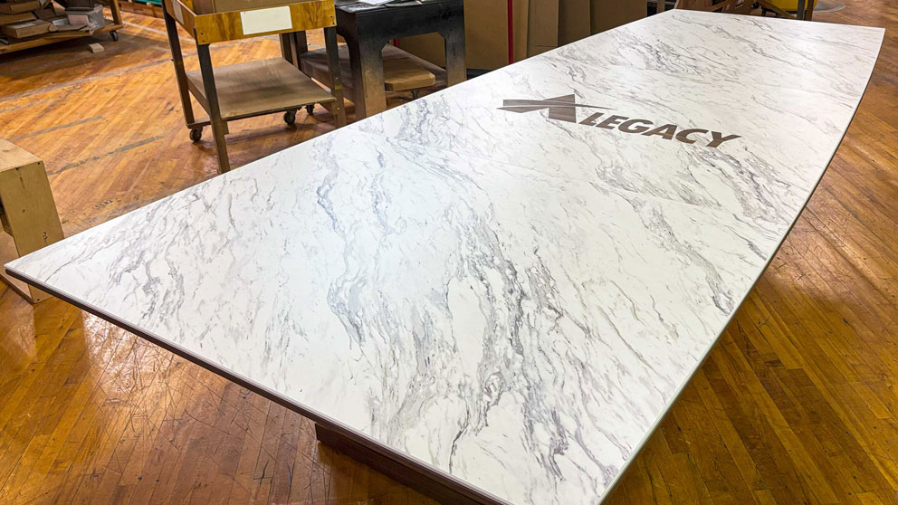 Custom boardroom table with integrated brand inlay and stone-look laminate surface
